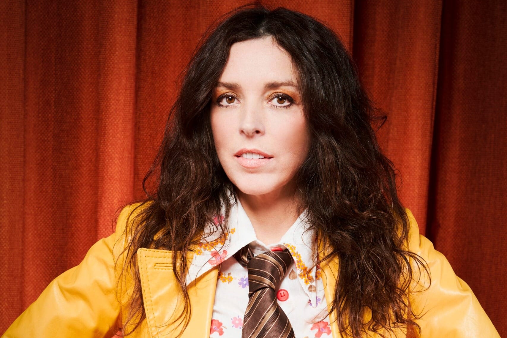 A woman and and orange jacket with a short and tie