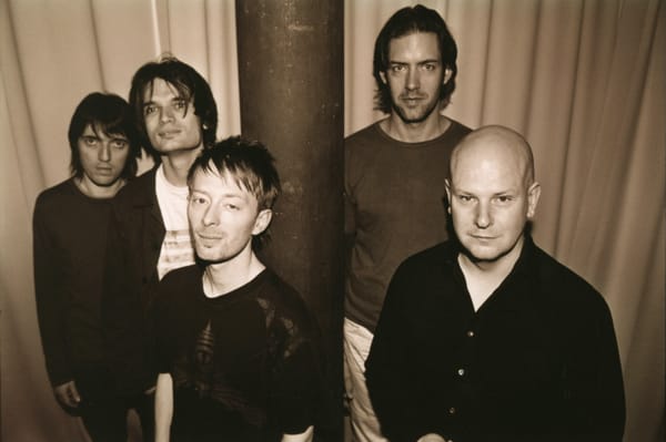 Five men (members of the band Radiohead) stand around a pole in a black and white photograph