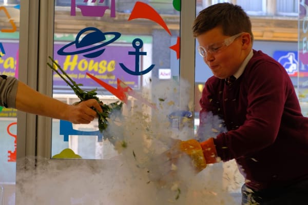 A boy wearing goggles and gloves holds a bunch of flowers that appear to be exploding