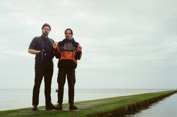 Two men stand on a sea wall